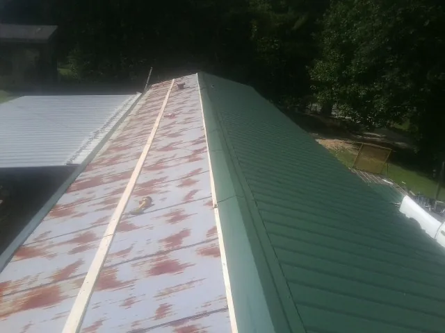 Old rusted panels beside newly installed green metal roofing — Wind Damage Roof Repair by Roofing Brothers in Cherryville