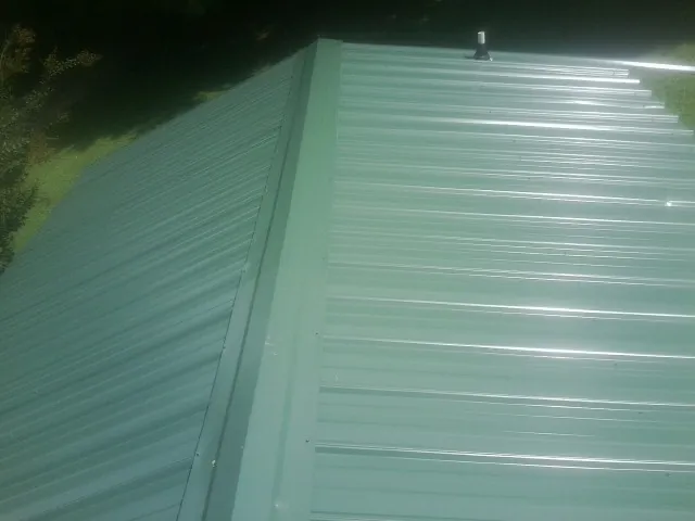 New green metal panels meeting at the ridge of a roof — Flat Roof Repair work by our crew in Cherryville