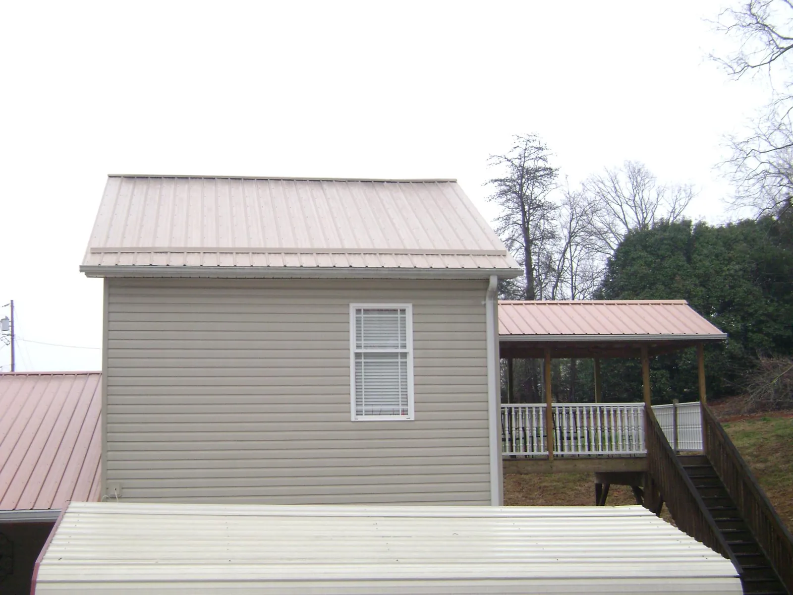 Tan metal roofs on a two story addition and attached porch, from a Roof Replacement job in Cherryville